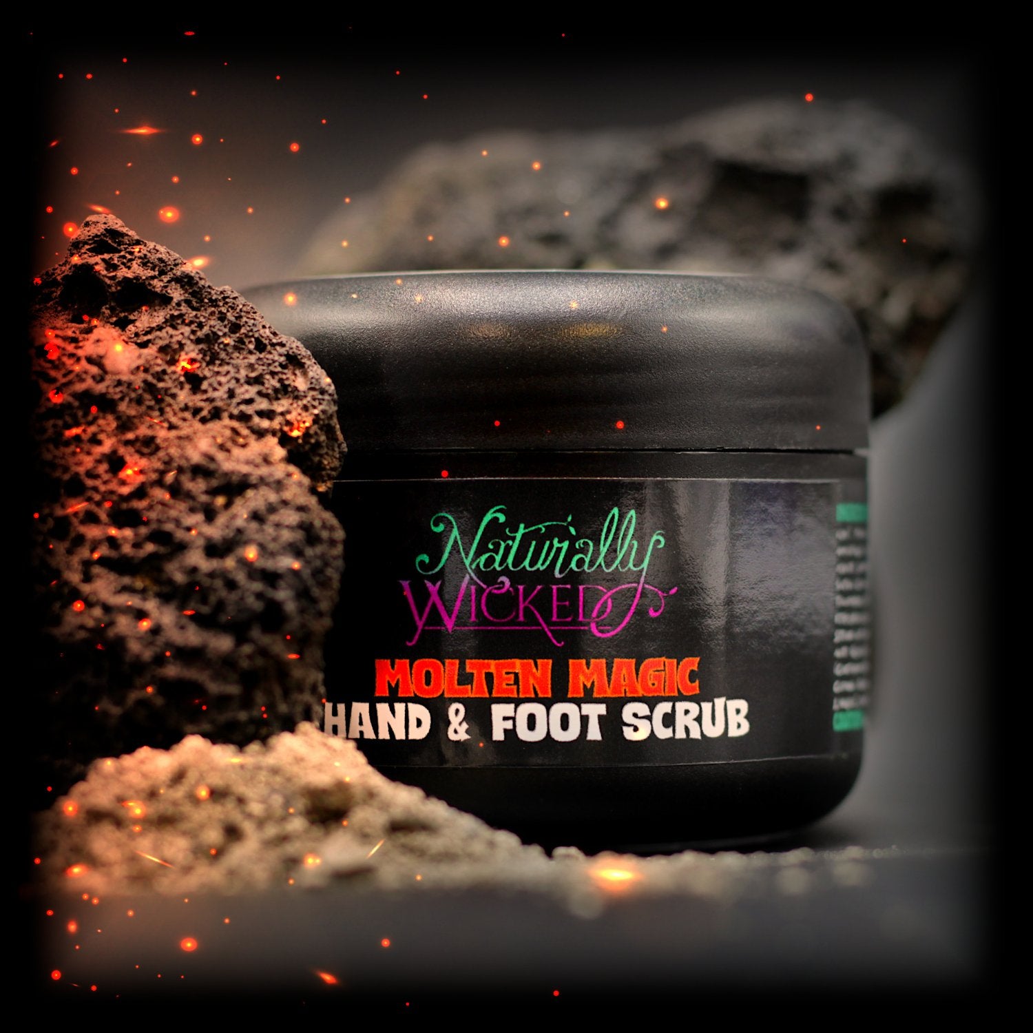 Naturally Wicked Molten Magic Hand & Foot Scrub In Luxury Black Container Beside Hot Embers & Volcanic Rock